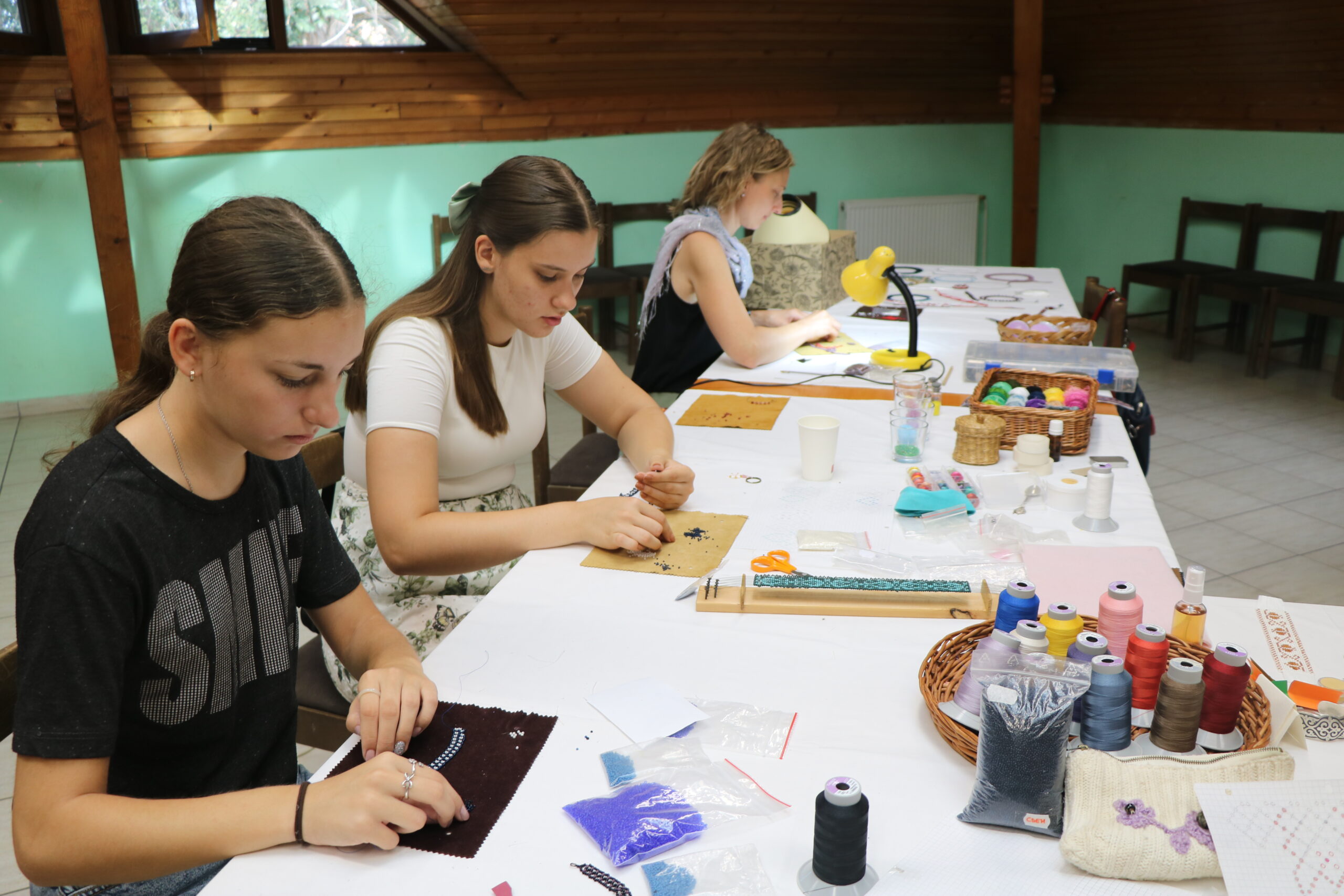Fiatal gyöngyfűzők munkában a népi kézműves táborban Tóthfaluban augusztus 2. és 9. között (Fotó: Hagyományok Háza)